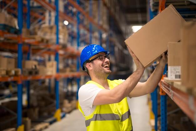 Warehouse worker arranging carton box in suitable rack happily
