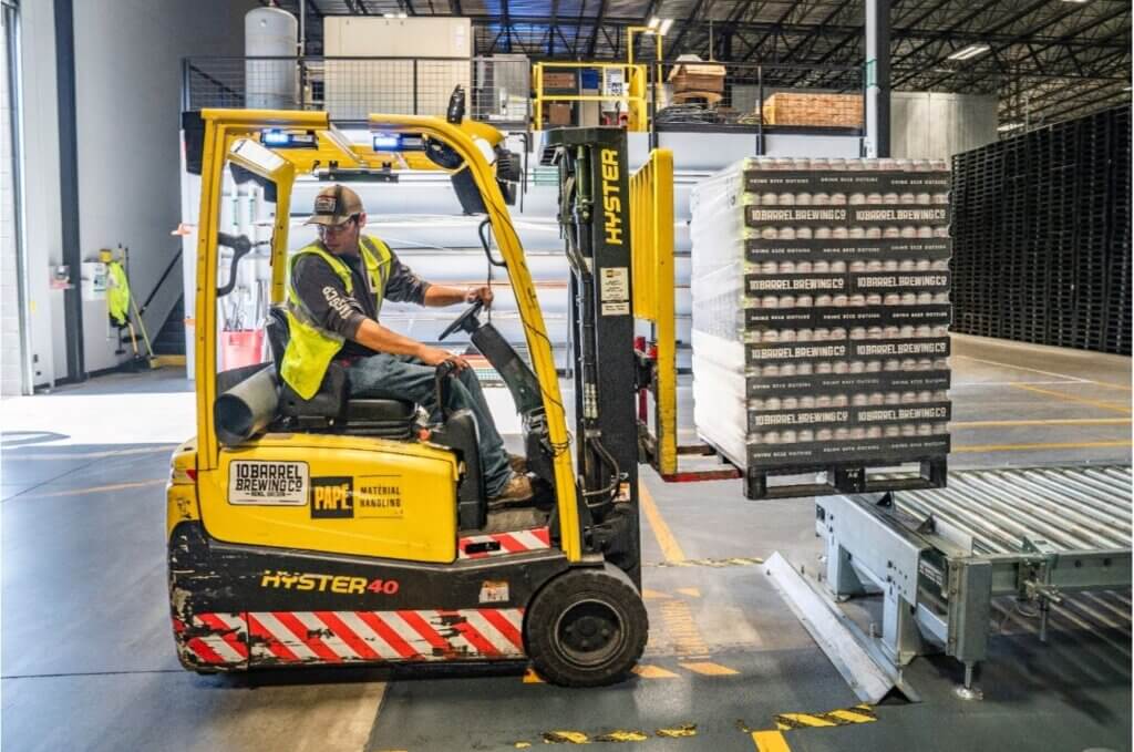 Forklift driver lifting materials from conveyor
