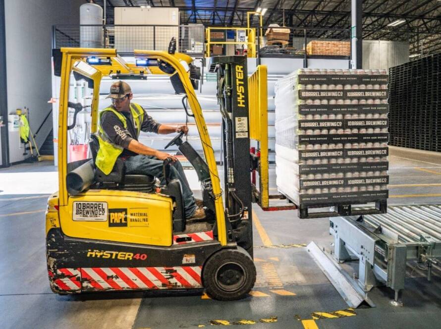 Forklift driver lifting materials from conveyor